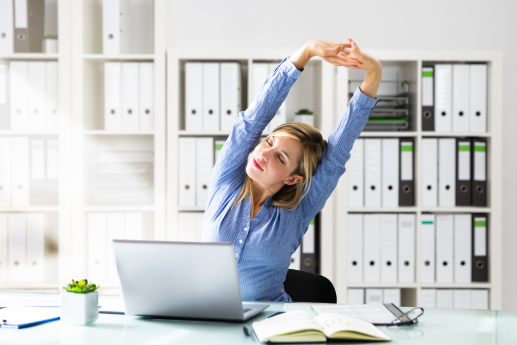 Woman sits at the desk and stretches