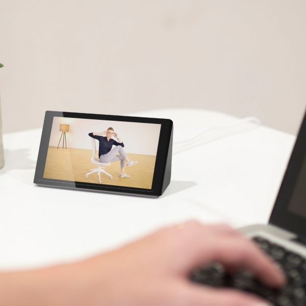 Isa stands on a desk and plays a video of an exercise programme. It shows a woman doing sport on her office chair.